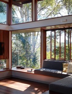 a living room with wood floors and large windows looking out onto the trees outside,