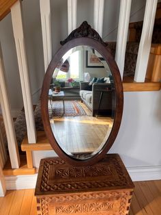 a mirror sitting on top of a wooden table in front of a stair case next to a window