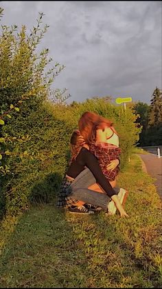 a woman sitting on the ground next to bushes