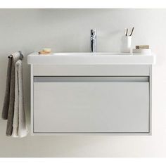 a white bathroom vanity with two towels hanging on the wall