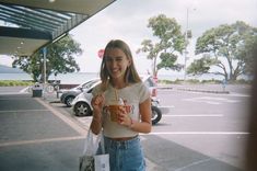 a young woman is holding a drink and shopping bags