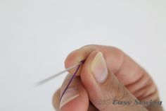 a person is holding a needle in their left hand and pointing it at the thread