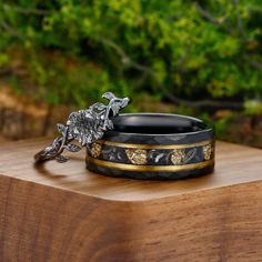 two black and gold rings sitting on top of a wooden table next to some trees