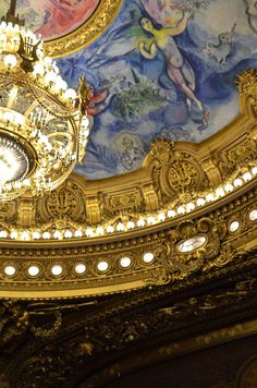 an ornate ceiling with chandelier and paintings on the walls in a theatre or theater