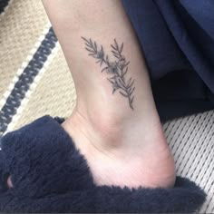 a small tattoo on the ankle of a woman's foot, with flowers and leaves