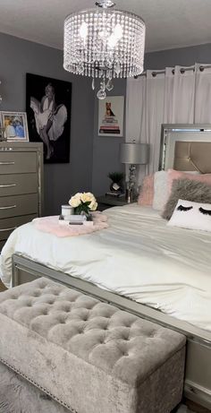 a bedroom with a bed, dresser and chandelier