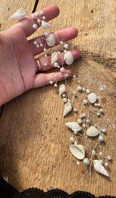 someone is holding their hand over some seashells on a wooden table with other shells