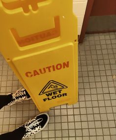 a person standing next to a caution wet floor sign