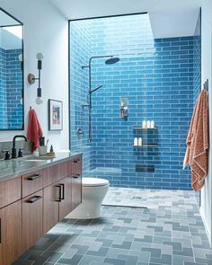 a bathroom with blue tiles on the walls and floor, along with a walk in shower