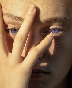 a close up of a person holding their hands to their face with the sun shining on them