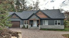 a gray house surrounded by trees and rocks