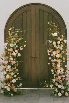 an arched wooden door with flowers on it