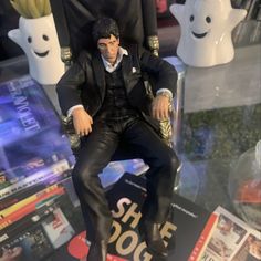 a figurine sitting on top of a book in front of a table full of books