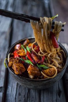 a bowl filled with noodles and meat on top of a wooden table