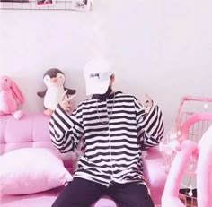 a man sitting on top of a pink couch next to a penguin doll and stuffed animal