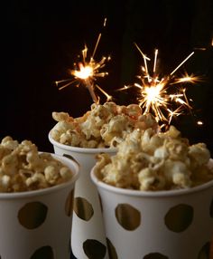 three white cups filled with popcorn and sparklers