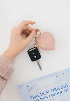 a person is holding a car keychain and it has a heart shaped case