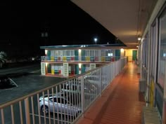 an empty parking lot at night with cars parked on the side of the road and motels in the background