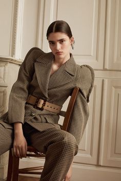 a woman sitting in a chair wearing a suit