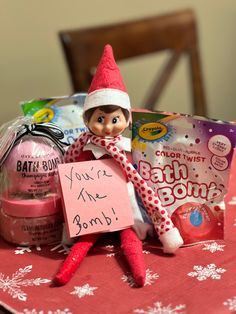 an elf is holding a sign on top of a table with candy and candies