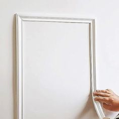 a person is painting a white frame on the wall