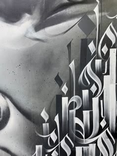 an artistic painting on the side of a building with arabic writing in black and white