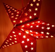 a red and white star shaped light hanging from a ceiling with stars on the side