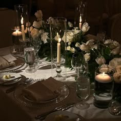 the table is set with candles, plates and silverware for an elegant dinner party