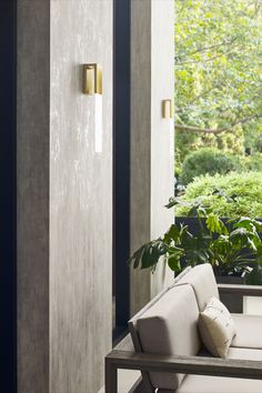 a white couch sitting in front of a window next to a potted green plant