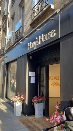 the front entrance to a flower shop with flowers in large planters on the sidewalk