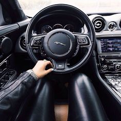 the interior of a car is shown with black leather and wood trims, while someone's hands are on the steering wheel