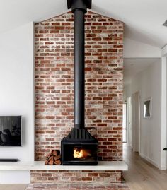 a large brick fireplace in the middle of a living room with hardwood floors and white walls