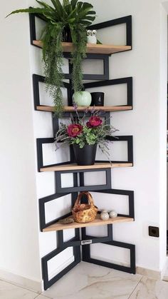 a corner shelf with potted plants and other items on it in a white room