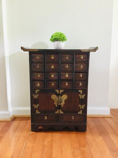 a wooden dresser with many drawers and a potted plant on top