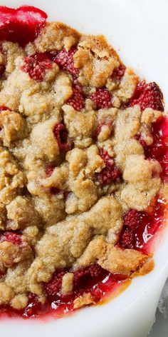 a close up of a pie on a plate with strawberries and crumbs