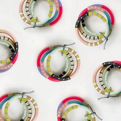 six colorful bracelets are arranged on a white surface, with string attached to them