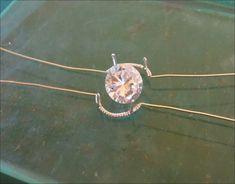 a diamond is sitting on top of a green surface with gold wires and beads around it