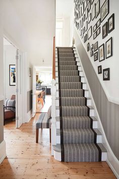 the stairs in this house are lined with pictures on the wall and carpeted floor