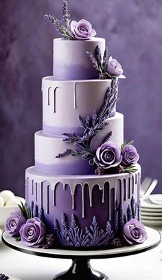 a three tiered cake with purple icing and flowers on the top is sitting on a plate