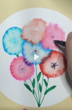 someone is drawing flowers on a white paper