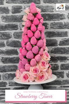 a cake with pink frosting and flowers on it is sitting in front of a brick wall