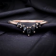 a black diamond ring sitting on top of a purple cloth