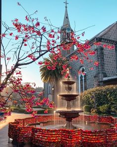 a fountain with flowers on it in front of a church