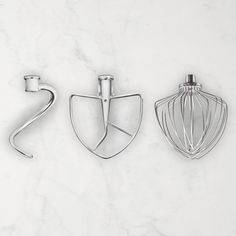 three kitchen utensils sitting on top of a white counter