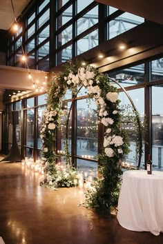 a wedding arch decorated with flowers and candles in front of a window overlooking the water