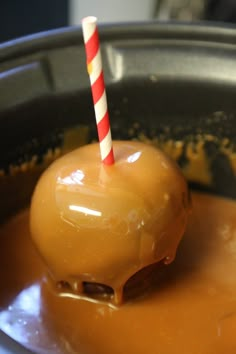 a caramel covered dessert with a single striped stick sticking out of it