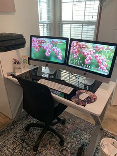 two computer monitors sitting on top of a desk next to each other in front of a window