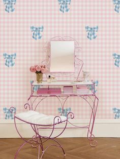 a pink and blue checkered wallpaper with a vanity, mirror and stool in front of it