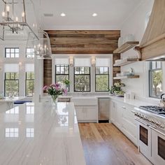 a large kitchen with white cabinets and marble counter tops, wood paneling on the walls