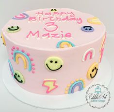 a pink birthday cake decorated with smiley faces